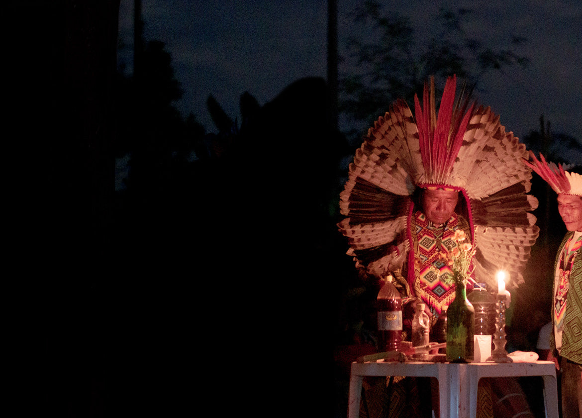 Huni Kuin elders in feathered headdresses at a candlelit ceremony in Acre