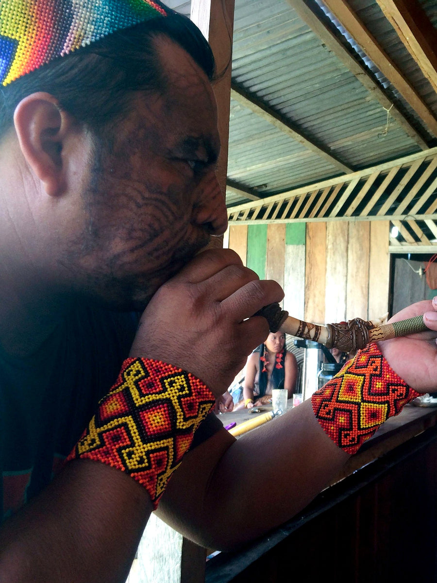 A Yawanawá shaman administers rapé using a traditional tepi pipe
